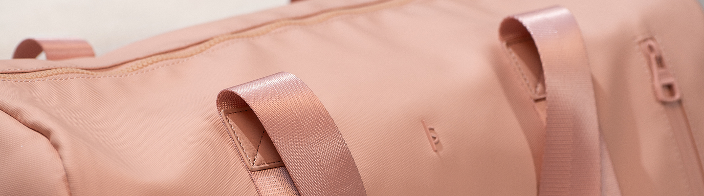 Close-up of a pink bag with ribbons on a light beige background