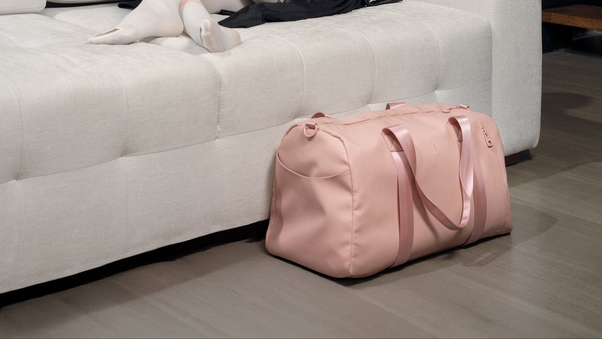 pink duffel bag next to her in a room with panelled walls.