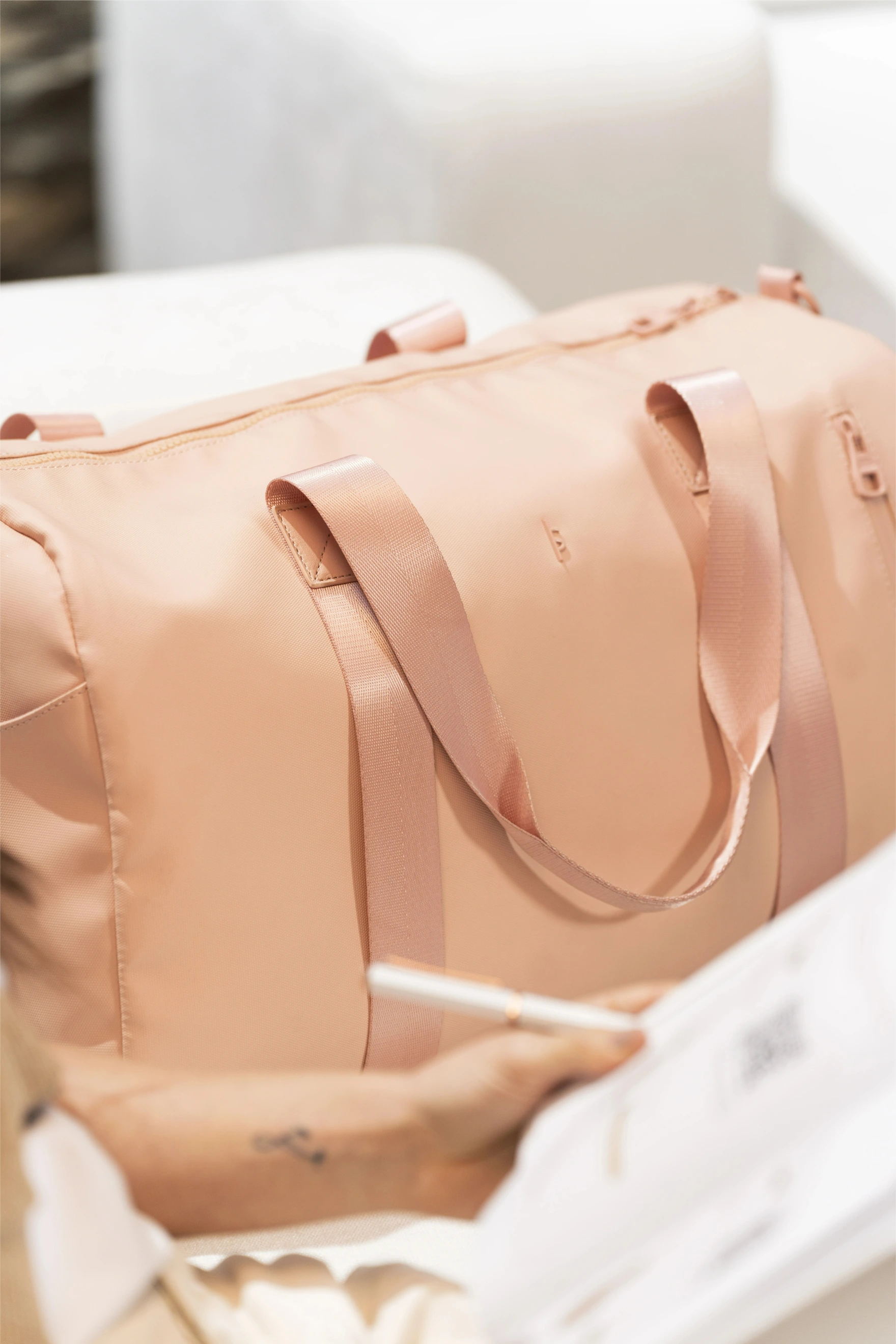 Beige duffel bag with a handle on a white surface